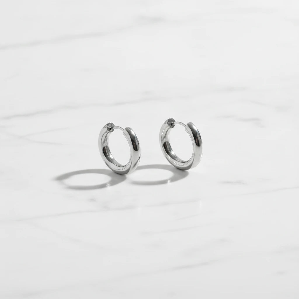 LUCIA EARRINGS | Place the original product large and centered on a clean white marble surface with a matching white marble background.