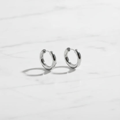 LUCIA EARRINGS | Place the original product large and centered on a clean white marble surface with a matching white marble background.