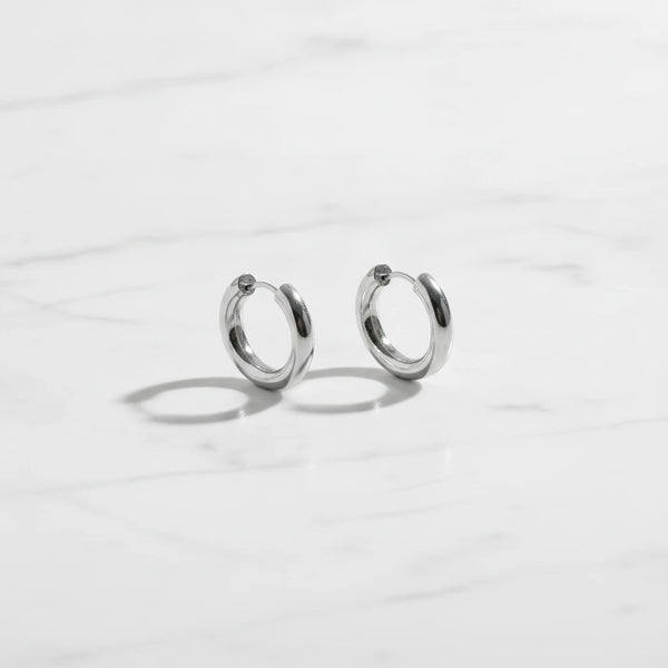 LUCIA EARRINGS | Place the original product large and centered on a clean white marble surface with a matching white marble background.