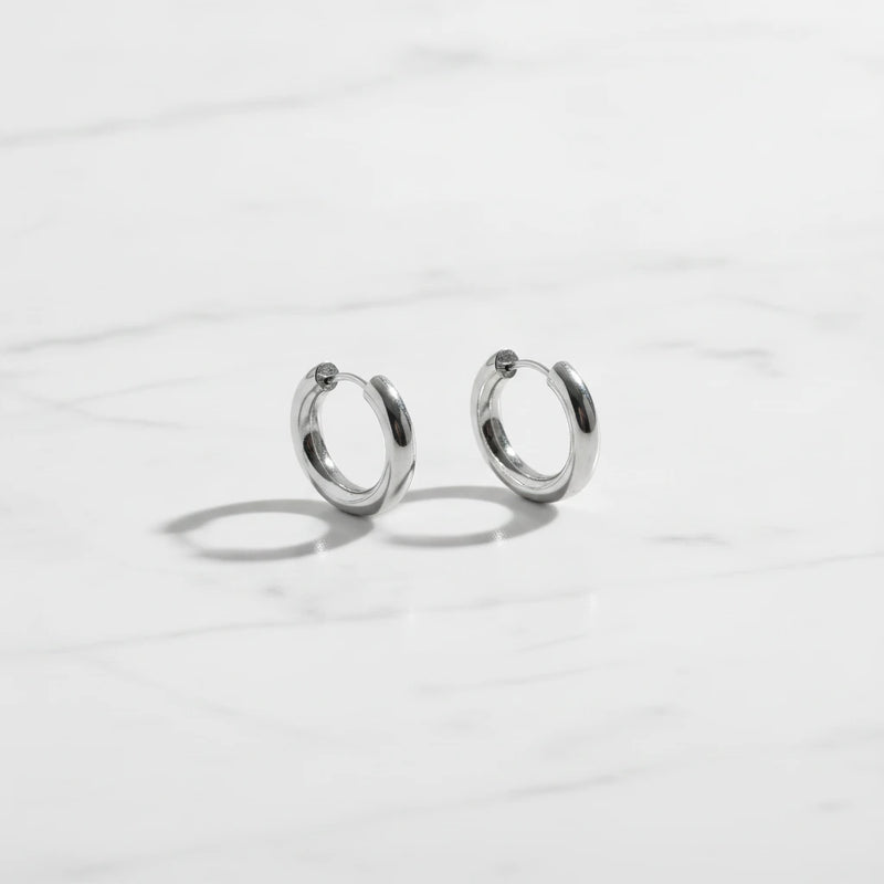 LUCIA EARRINGS | Place the original product large and centered on a clean white marble surface with a matching white marble background.