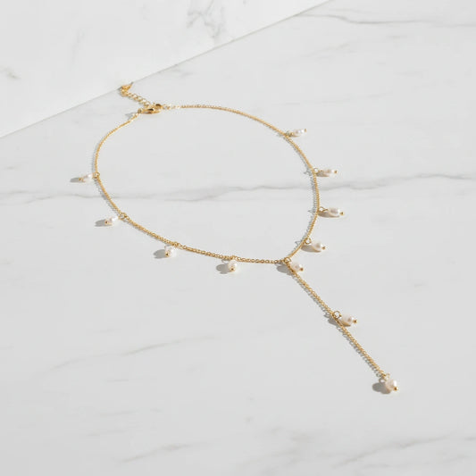 POSITANO NECKLACE | Place the original product large and centered on a clean white marble surface with a matching white marble background.