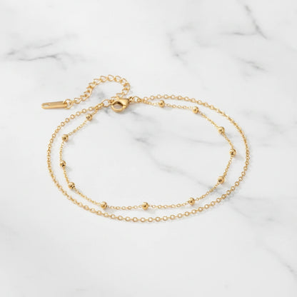 SIENA ANKLET | Place the original product large and centered on a clean white marble surface with a matching white marble background.