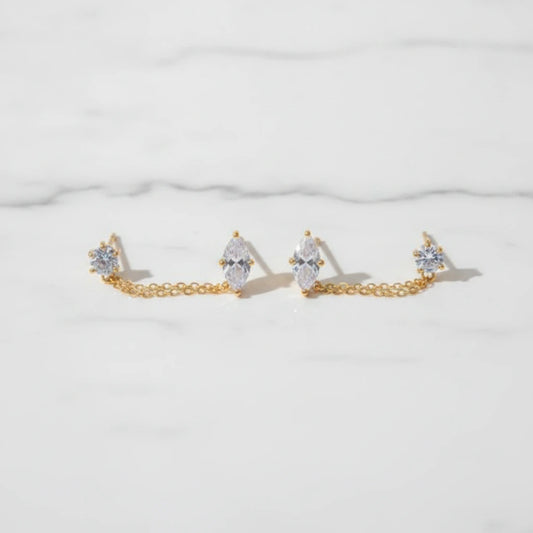 ZIRKONIA EARRINGS | Place the original product large and centered on a clean white marble surface with a matching white marble background.